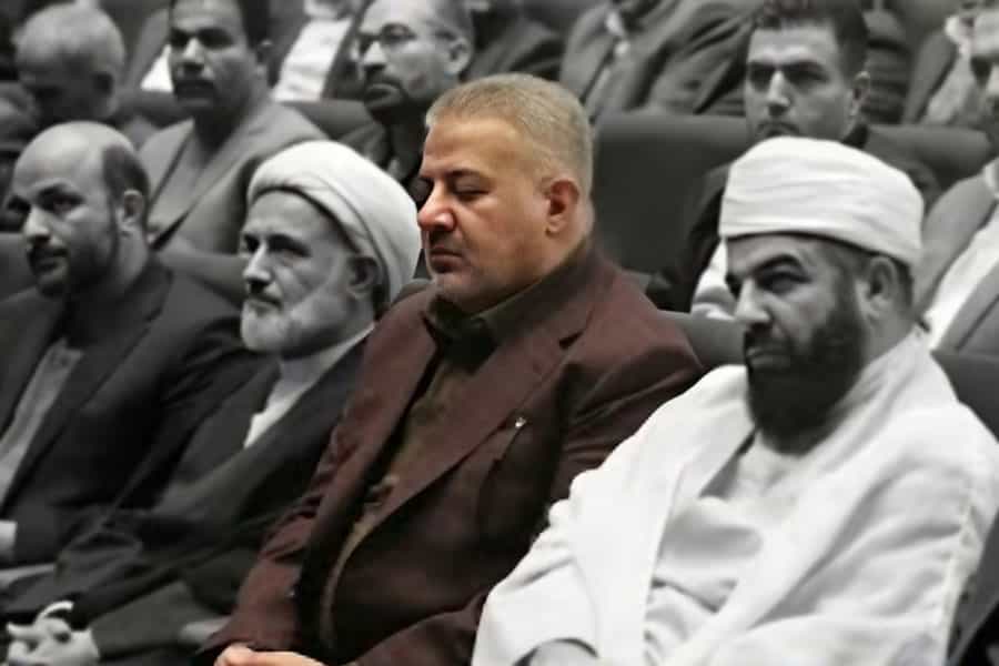 ناجی ابراهیم شریفی-زیندشتی در میان عدهای از جمله دو روحانی نشسته است.