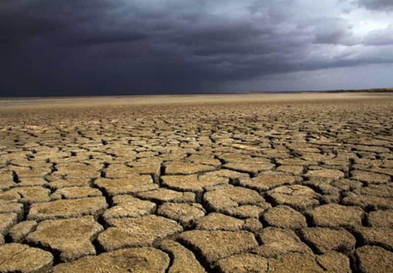 زمین ترک خورده بیابانی و آسمان تیره
