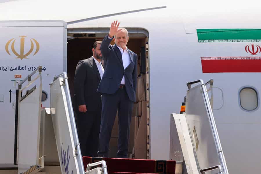 مسعود پزشکیان روی پلکان هواپیما دست تکان میدهد.
