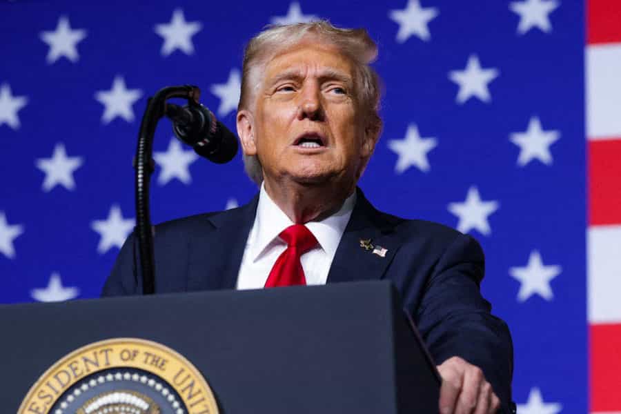 دونالد ترامپ پشت تریبون در حال سخنرانی است و پشت سر او پرچم ایالات متحده آمریکا دیده میشود.