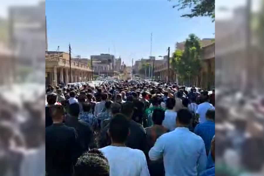 کارگران گروه ملی فولاد ایران (اهواز) در خیابان در حال تظاهرات هستند. تصویر آنها از پشت سر دیده میشود.
