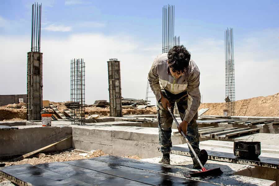 یک کارگر افغانستانی در حین کار ساختمانی قیرگونی می‌کند.