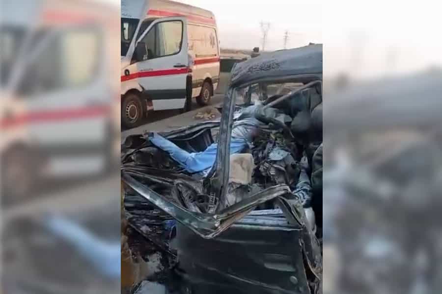 یک خودرو ویران‌شده و با دو جسد درون آن در کنار یک آمبولانس دیده می‌شود.