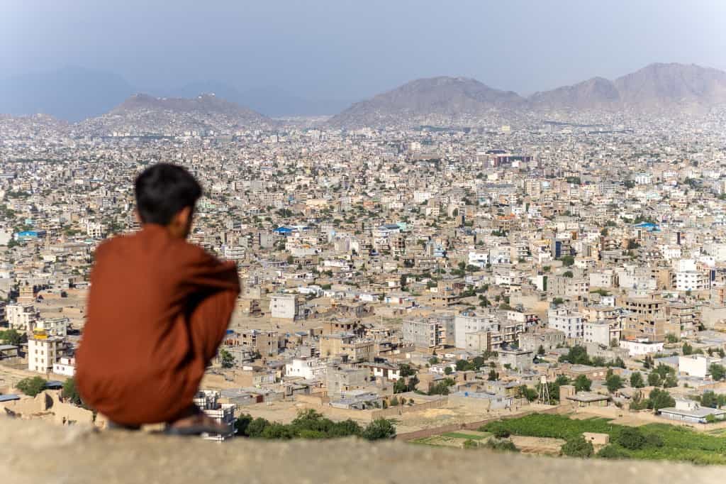 یک پسر در ۱۳ ژوئن ۲۰۲۵ به کابل، افغانستان نگاه می‌کند. پایتخت افغانستان که توسط کوه‌ها احاطه شده است، دهه‌ها درگیری و بازسازی را با محله‌های شلوغ، مساجد و ساختمان‌های نیمه‌کاره خود منعکس می‌کند.