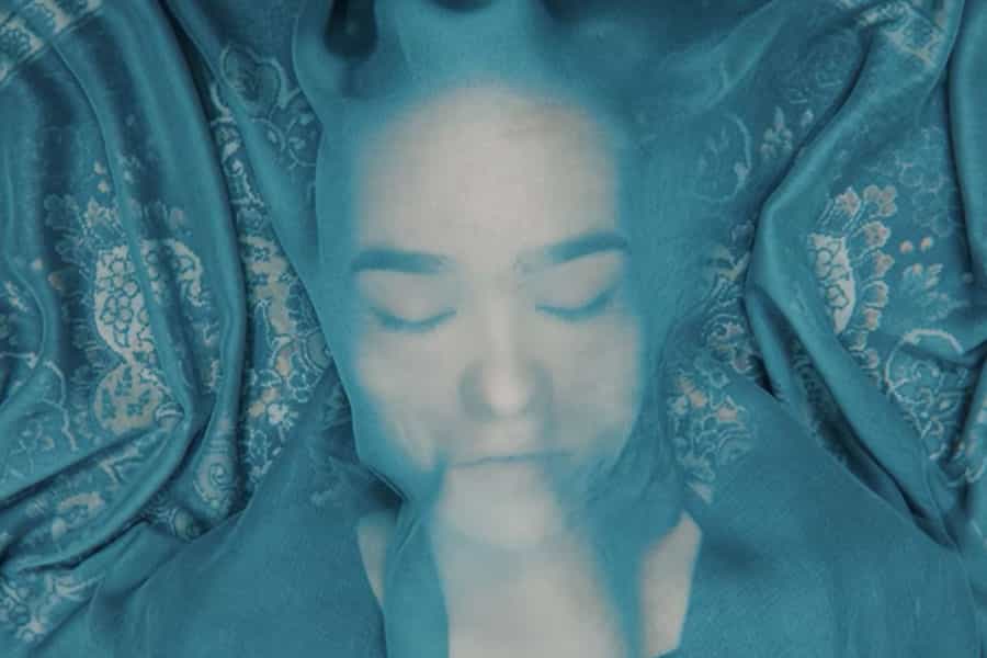 صورت یک دختر افغان زیر یک توری دیده می‌شود. او چشمانش بسته است و تمام فضا آبی است.