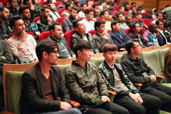 تصویر یک آمفیتئاتر دانشگاه در ایران که چند دانشجوی افغانستانی در ردیفی از این سالن نشستهاند.