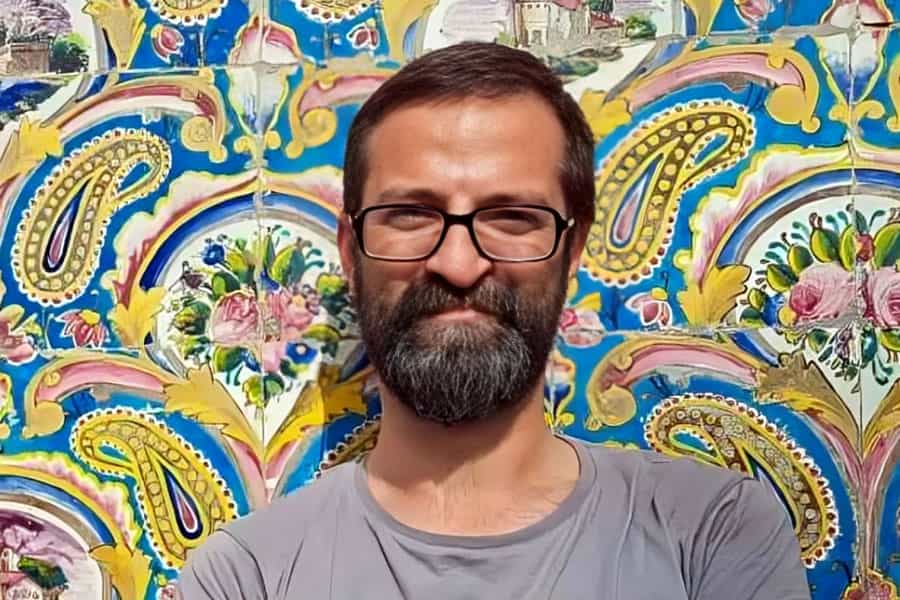 چهره فؤاد شمس زیر آفتاب در مقابل کاشیهای با نقوش ایرانی