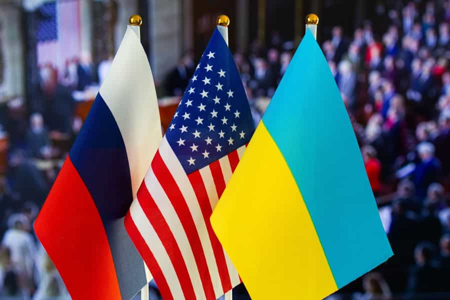 در تصویر، سه پرچم کشورهای اوکراین، ایالات متحده آمریکا و روسیه، و در پس‌زمینه آن کنگره آمریکا به‌شکل محو دیده می‌شود.