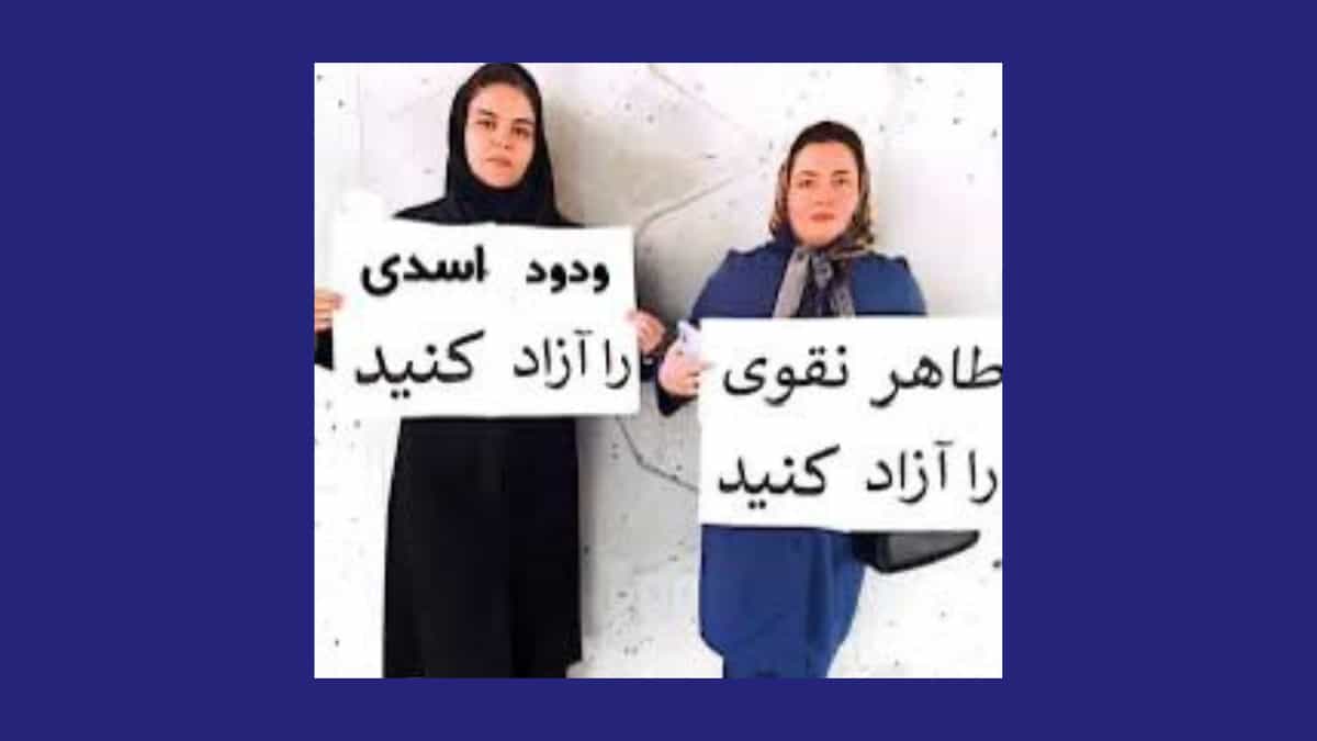 دو زن که پلاکاردی برای ازادی طاهر نقوی و ودود اسدی در دست گرفته اند