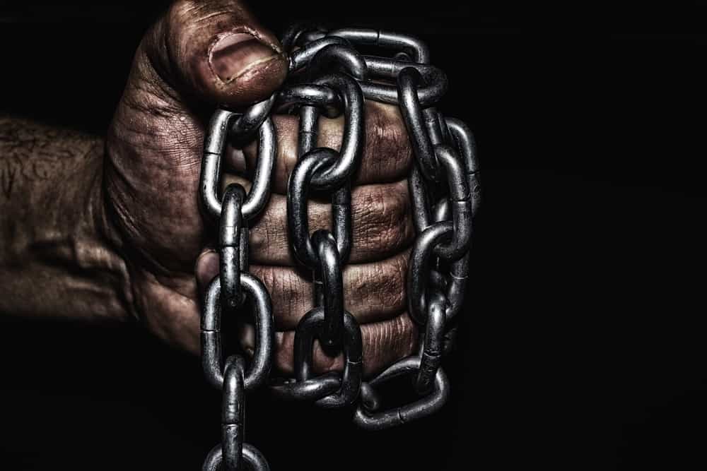 دستی که شبیه دست زحمت‌کشان و کارگران طراحی شده و به روغن آغشته است یک زنجیر را به صورت مشت شده گرفته است.