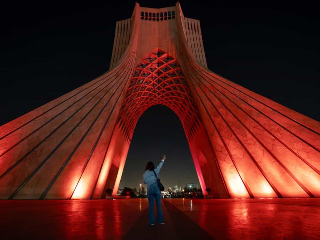 یک زن در ساعات پایانی روز در نزدیکی برج آزادی عکس میگیرد،