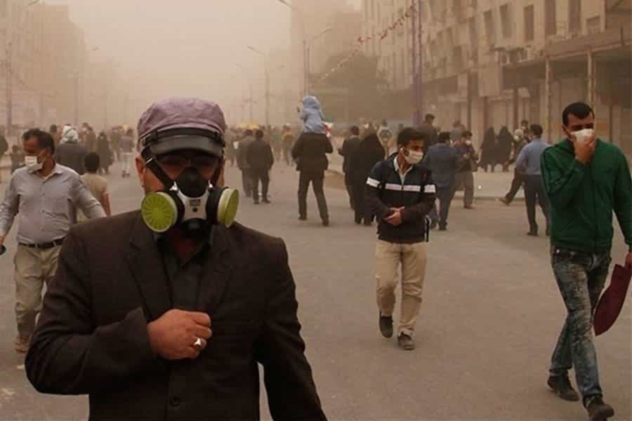 مردم در یک هوای به‌شدت آلوده ماسک زده‌اند و در خیابان راه می‌روند. یک نفر ماسک ضد مواد شیمیایی زده است.