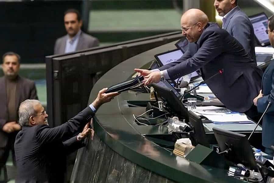 مسعود پزشکیان پشت تریبون مجلس دست خود را به سوی محمدباقر قالیباف دراز کرده و لایحه بودجه سال ۱۴۰۵ به او می‌دهد.