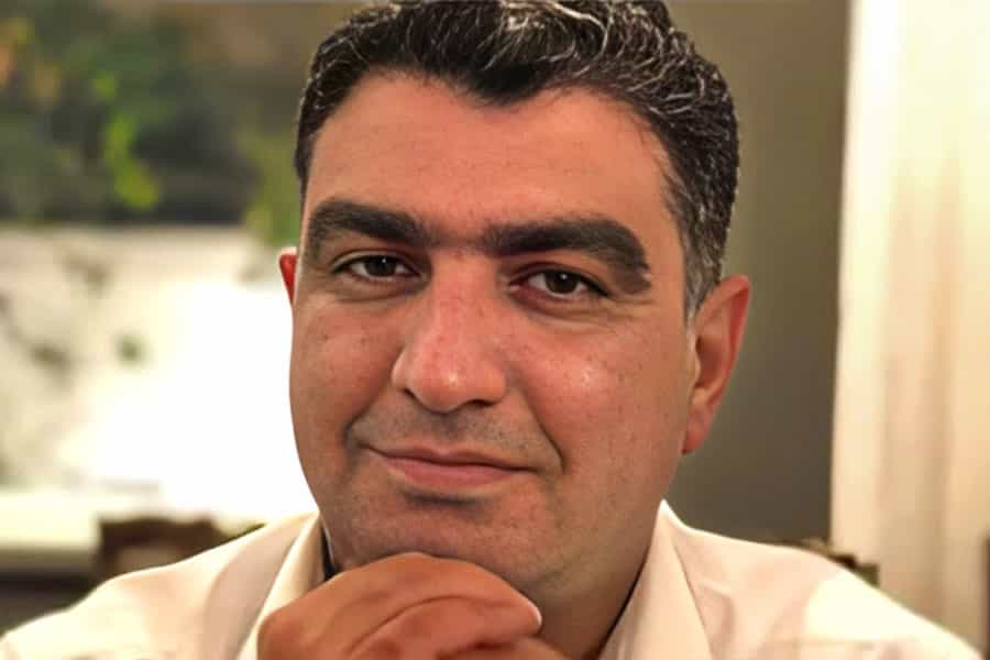 تصویری نزدیک از چهره خسرو علیکردی. او دست خود را زیر چانه گذاشته و به دوربین لبخند میزند.