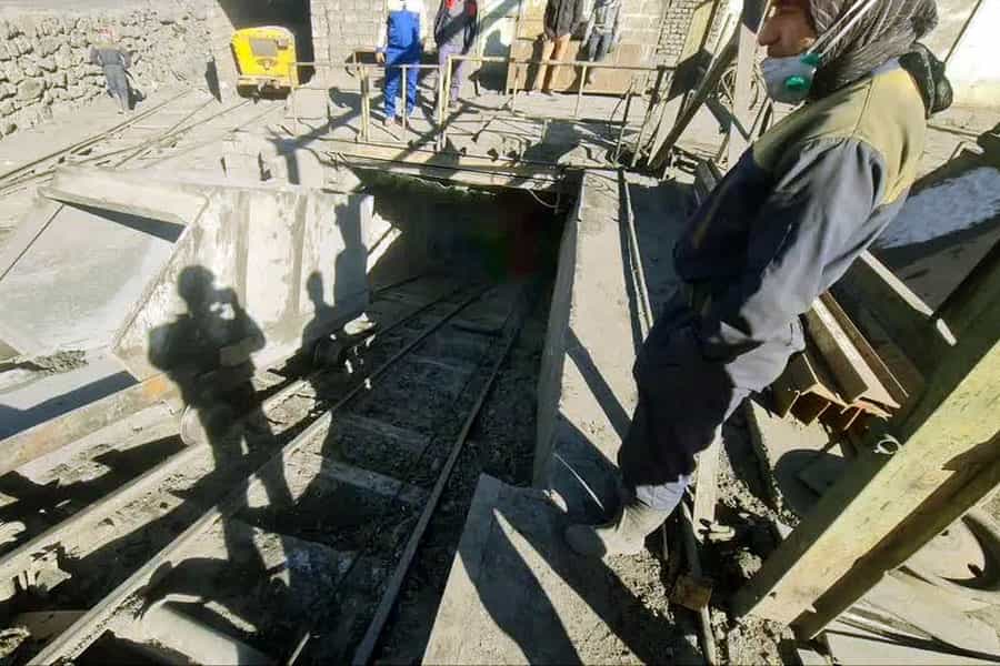 چند کارگر در ورودی معدن سنگ آهن بافق ایستادهاند.