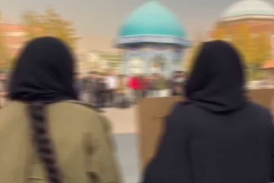 تصویری از تجمع اعتراضی گروهی از دانشجویان دانشجویان دانشگاه علامه طباطبایی ـ تصویر مات شده است اما دو دختر از پشت سر دیده میشوند.