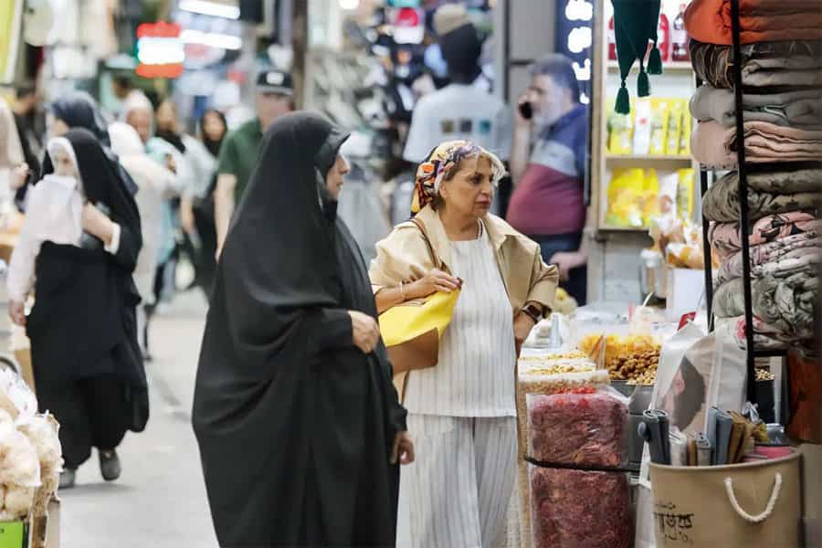دو زن در بازار در حال تماشای اجناس هستند.