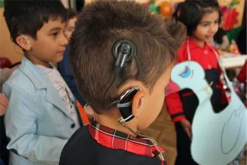 چند کودک در تصویر دیده می‌شوند که سمعک در گوش دارند.