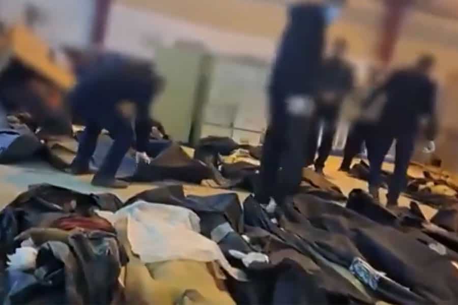 شماری جسد روی زمین یک سالن قرار دارند و عده‌ای در میان آن‌ها در حال شناسایی بستگان خود هستند.