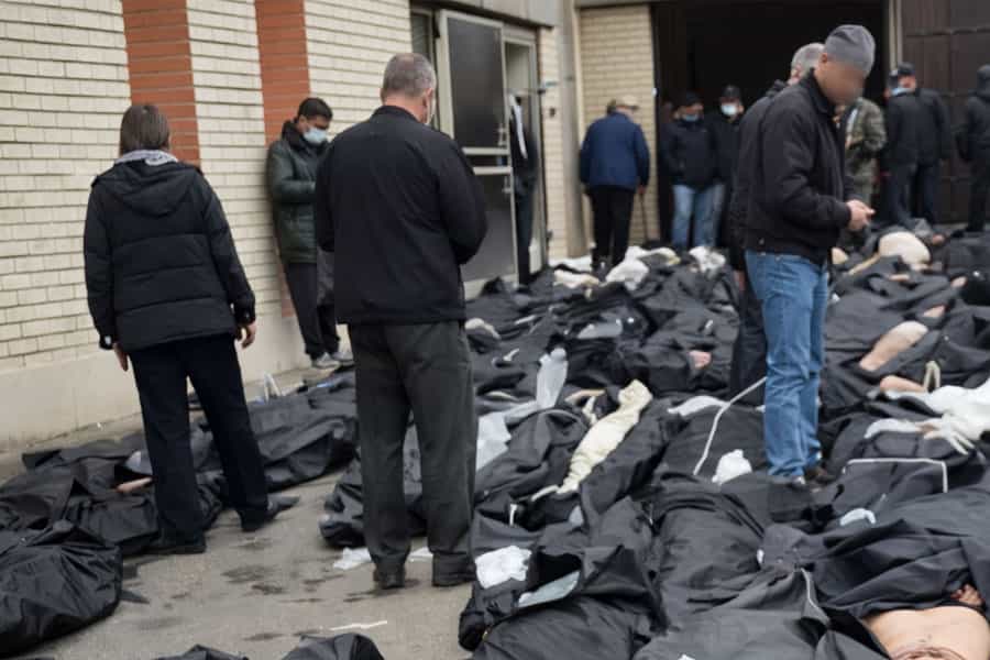 شماری جسد روی زمین یک سالن قرار دارند و عده‌ای در میان آن‌ها در حال شناسایی بستگان خود هستند.