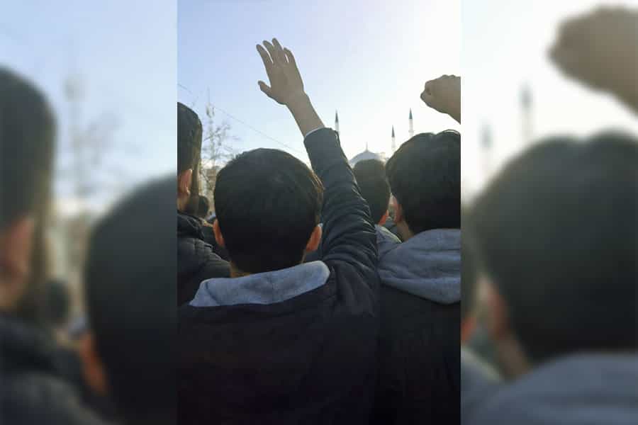 چند مرد بلوچ مشتهای خود را بلند کردهاند. آنها از پشت سر دیده میشوند.