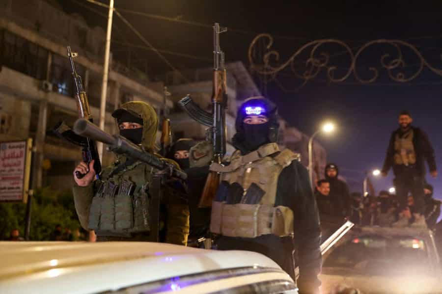 سربازان ارتش سوریه روی خودروهای نظامی با سلاح‌هایی در دست در حال عبور از خیابان‌های حلب هستند.