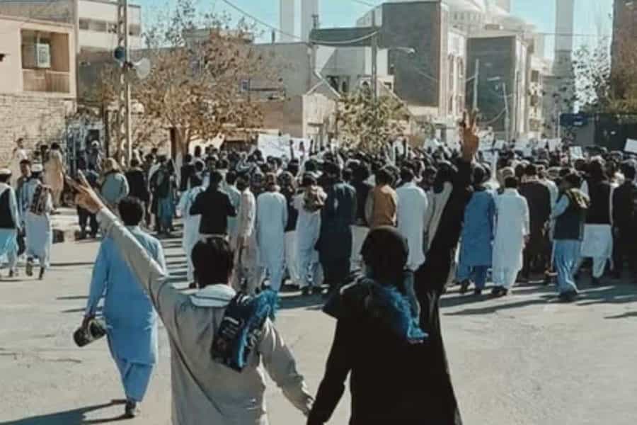 جمعیتی از بلوچها در حال تظاهرات هستند. دو نفر انگشتان خود را به علامت پیروزی بالا بردهاند.