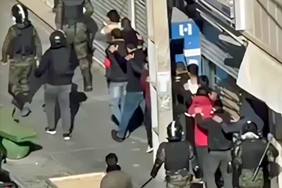 در پیاده‌رو یک خیابان مأموران امنیتی چند نفر از معترضان را بازداشت کرده و با خود می‌برند.