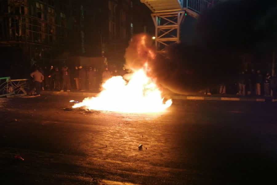 گروهی از مردم معترض در سیاهی شب آتشی در وسط خیابان بر پا کرده‌اند.