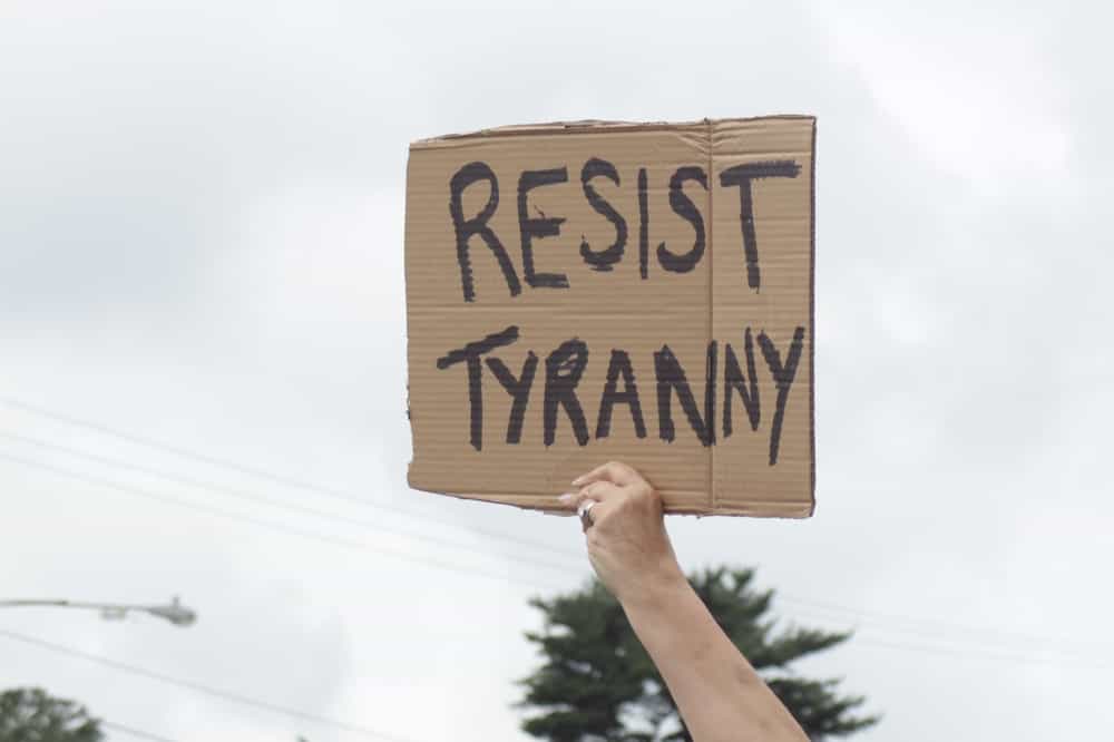 معترضی تابلویی برای اعتراض «بدون پادشاه» در دست دارد که روی آن نوشته شده «مقاومت در برابر استبداد».