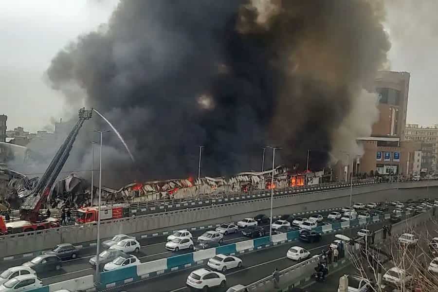 نمایی از آتش‌سوزی مهیب در بازارچه جنت‌آباد تهران با دود سنگین که از محل به آسمان برخاسته است.