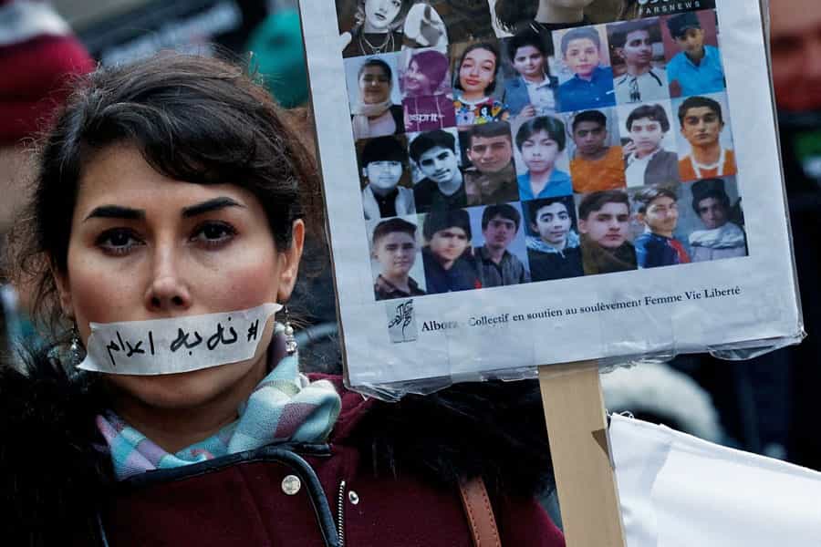 یک تظاهرکننده زن در جریان تظاهرات ایرانیان در پاریس برچسب «نه به اعدام» بر دهان چسبانده و عکس عده‌ای از کودکان کشته‌شده در اعتراضات سراسری دی‌ماه ۱۴۰۴ را در دست گرفته است.