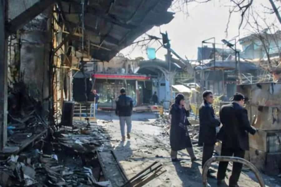 در میان ویرانه‌های سوخته بازار رشت چند نفر ایستاده‌اند.