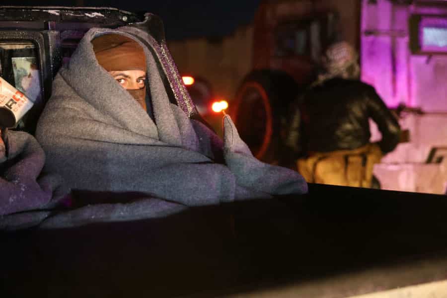 یکی از اعضای «نیروهای دموکراتیک سوریه» (SDF) در سرمای شب پتویی دور خود پیچیده است.