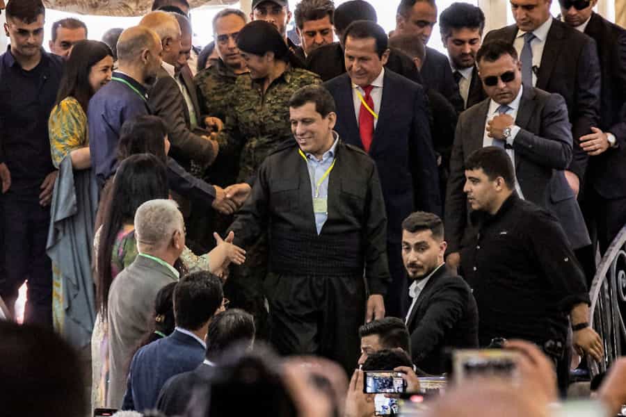 مظلوم عبدی در حال دست دادن با جمعیت حاضر است و می‌خندد.