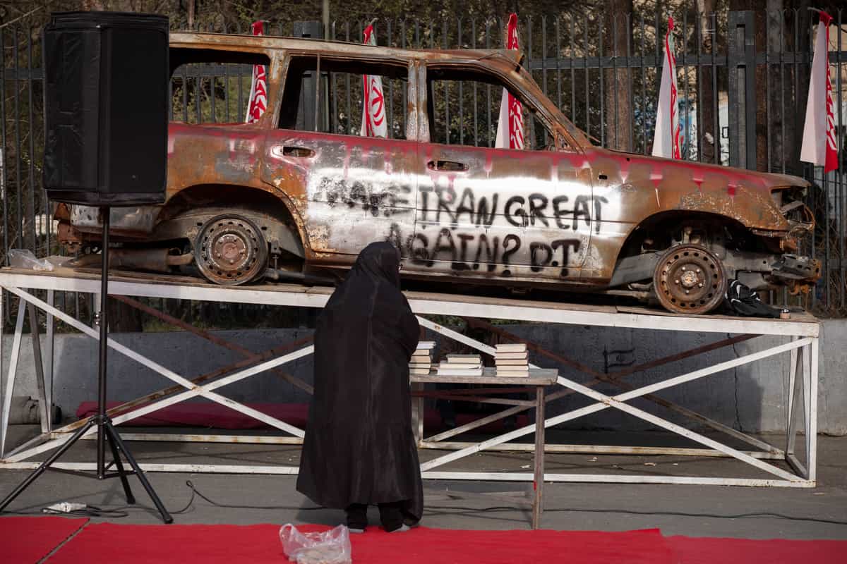 یک زن ایرانی محجبه در مقابل آمبولانسی که در طول جنگ ۱۲ روزه نابود شده ایستاده است، پیش از شرکت در مراسم تلاوت قرآن به مناسبت ماه مبارک رمضان، در میان کمپین آمریکا-اسرائیل، در بیرون دانشگاه تهران، ایران، در ۷ مارس ۲۰۲۶. (عکس از مرتضی نیکوبذل / نورفوتو) (عکس از مرتضی نیکوبذل / نورفوتو / نورفوتو از طریق AFP)