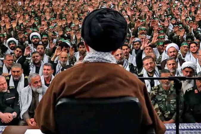 در این تصویر علی خامنهای از پشت سر نشان داده شده و گروهی زیادی از فرماندهان سپاه و روحانیان رو به دوربین به او نگاه میکنند.