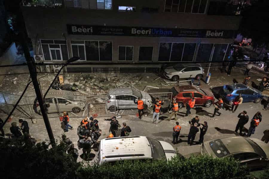 در کنار آوار پس از حملات موشکی ایران چند امدادگر اسرائیلی دیده می‌شوند. هوا تاریک است.