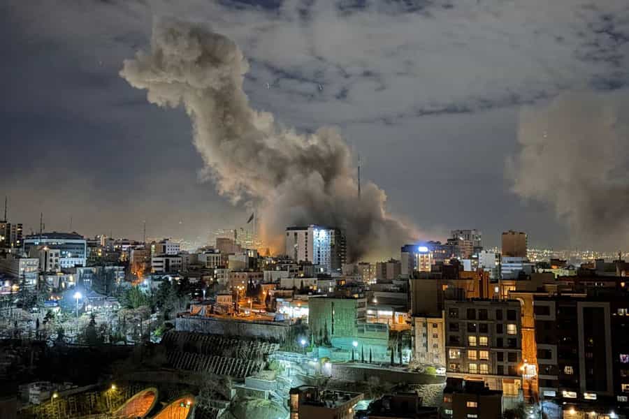 شب است و ساختمان‌های تهران در میان نورهای مختلف دیده می‌شوند. در انتهای تصویر دودی به آسمان برخاسته است.