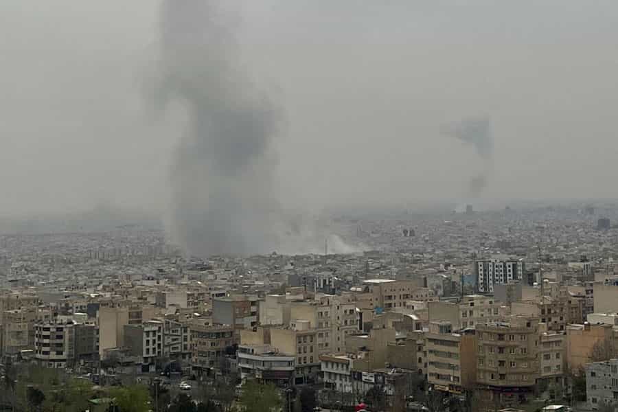 نمایی دور از تهران. بمبی در میان شهر منفجر شده است. روز است و هوا ابری است.