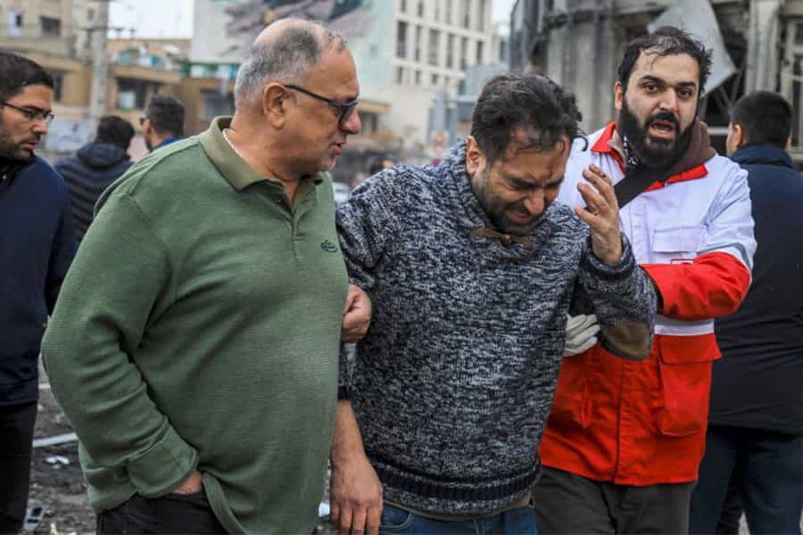 یک نیروی امدادگر به همراه یک نفر دیگر فردی را که مجروح شده است به جایی منتقل می‌کنند.