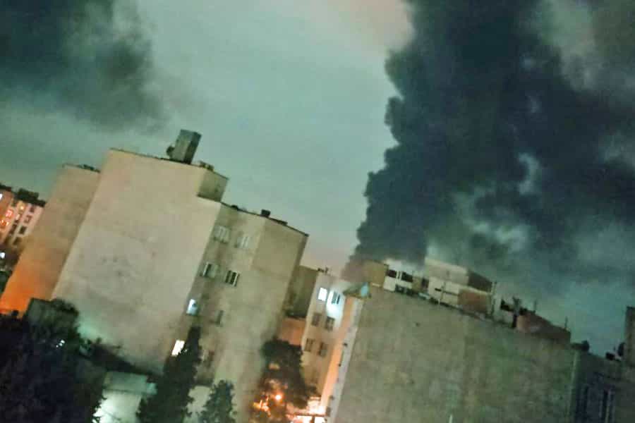 ساختمانهایی دیده میشوند که پشت سر آنها در آسمان بامدادی دو ستون دود ناشی از انفجار به آسمان برخاسته است.