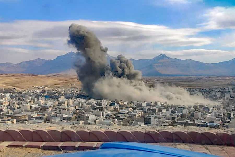 در انتهای یک بلوار، در دوردست، دود سیاه ناشی از یک انفجار شدید به آسمان برخاسته است. در بلوار چند خودرو در حال حرکتند و یک میوه فروش میوه‌های خود را در کنار بلوار قرار داده است.