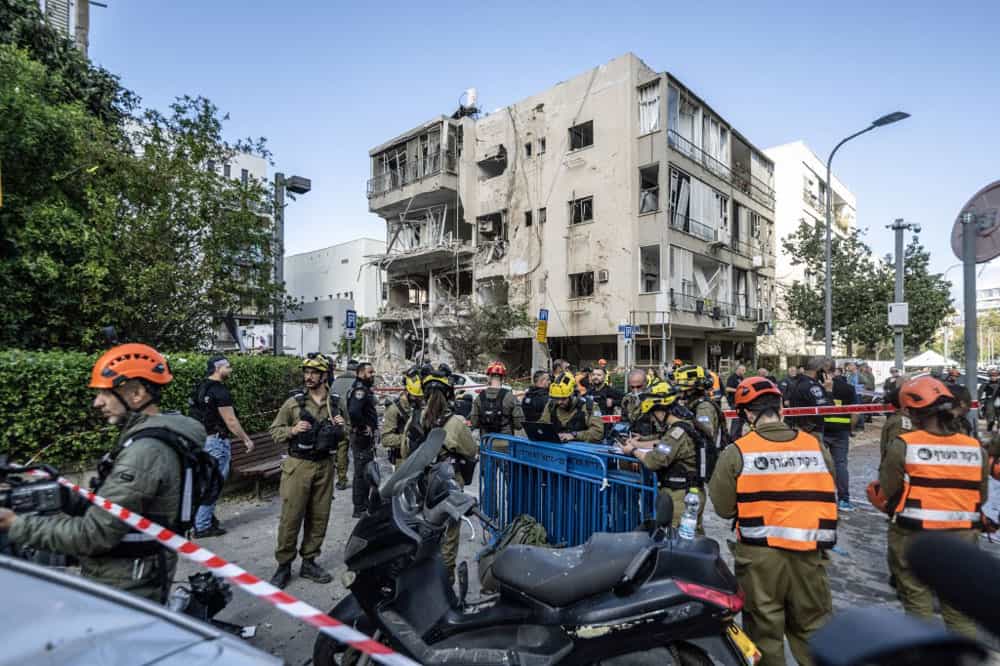 یک ساختمان مسکونی ویران شده و نیروهای امدادگر اسرائیلی در خیابان دیده می‌شوند.