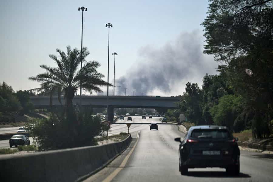 در اتوبانی در شهر کویت دود سیاهی در انتهای تصویر به آسمان برخاسته است.