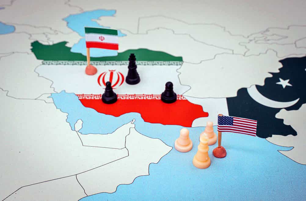 تصویری از نقشه ایران و پاکستان که با پرچم‌هایشان مشخص شده‌اند. یک پرچم آمریکا در خلیج فارس و چند مهره سرباز شطرنج نیز در اطراف آن دیده می‌شود.