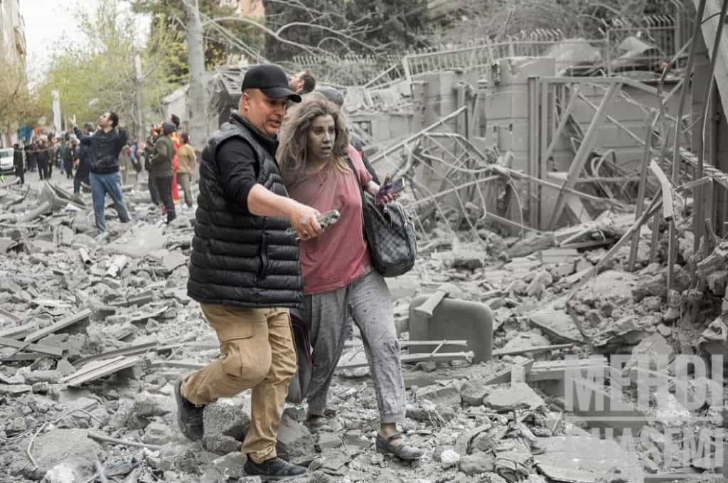 یک زن در میان ویرانه ها همراه یک مرد که به او کمک میکند