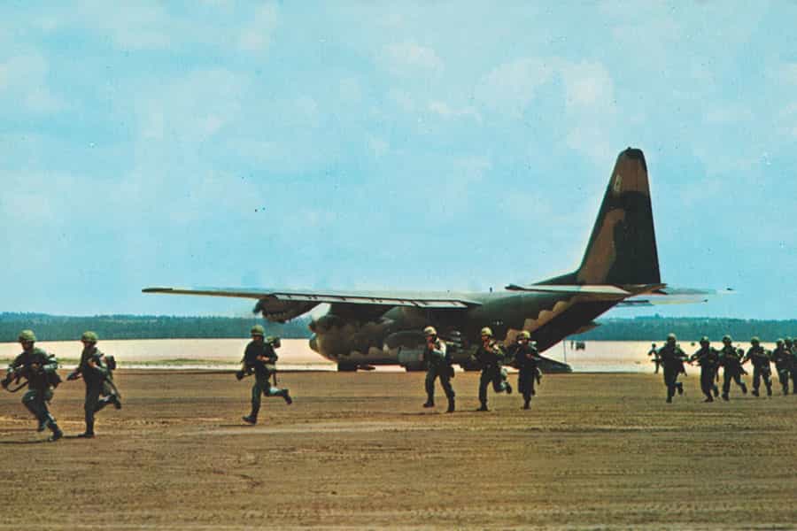 گروهی از سربازان آمریکایی در حالی‌که سلاح در دست دارند، در کنار یک هواپیمای نظامی در حال دویدن هستند.