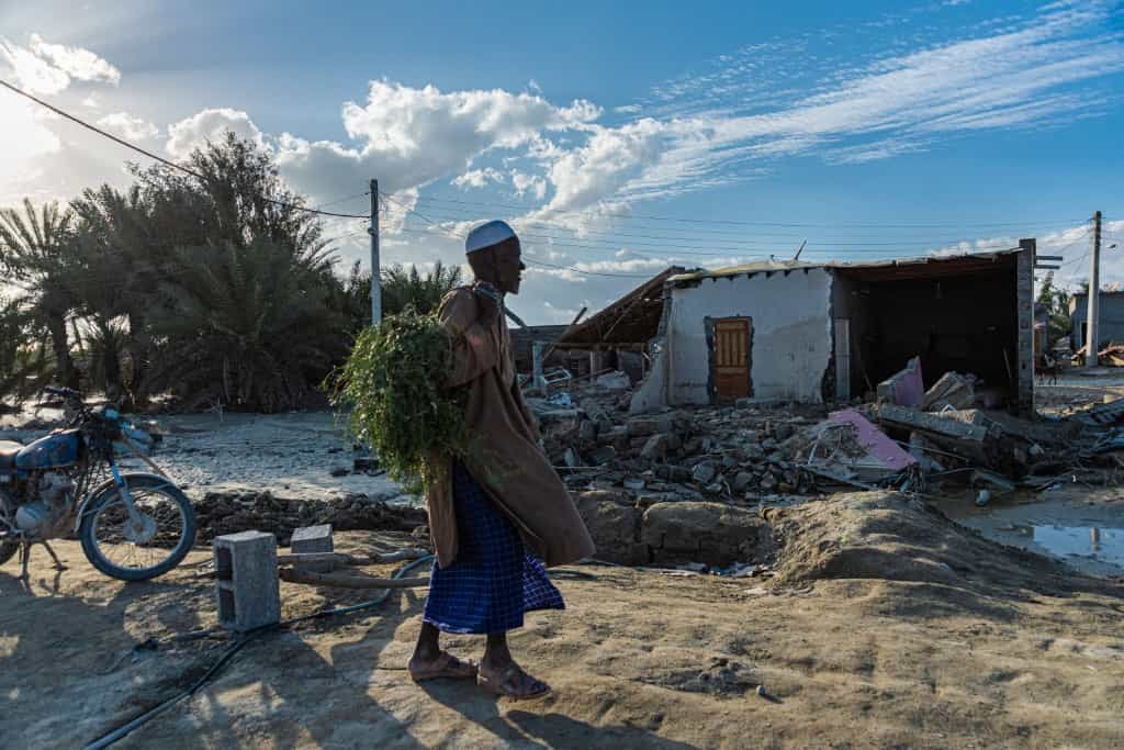 مردی در یک شهر چادری پس از وقوع سیل ناگهانی در مناطق زرآباد و دشتیاری در استان سیستان و بلوچستان، ایران، بوته‌ها را حمل می‌کند. ۲۰ ژانویه ۲۰۲۰.