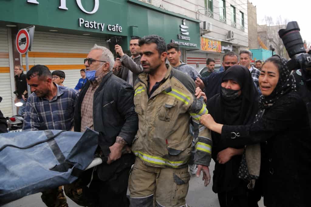 : تیمهای جستجو و نجات در حال حمل جسد بیجانی هستند که از زیر آوار یک خانه بیرون آورده شده است